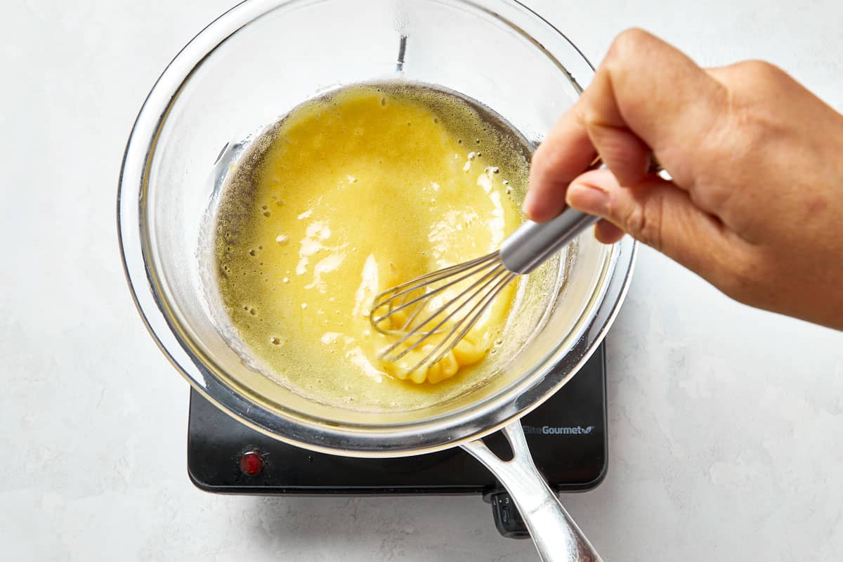 Folding mascarpone cheese into the warm egg mixture to create a smooth mascarpone cream for tiramisu cups.