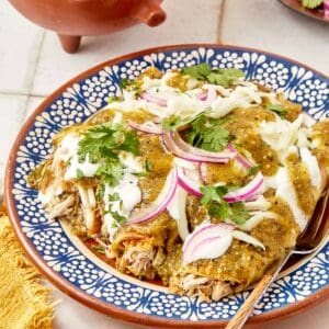 Mexican chicken enchiladas with a blue spoon.