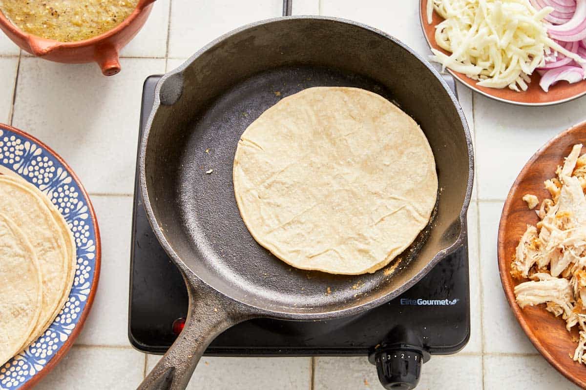 A skillet filled with soft tortillas and assorted ingredients.
