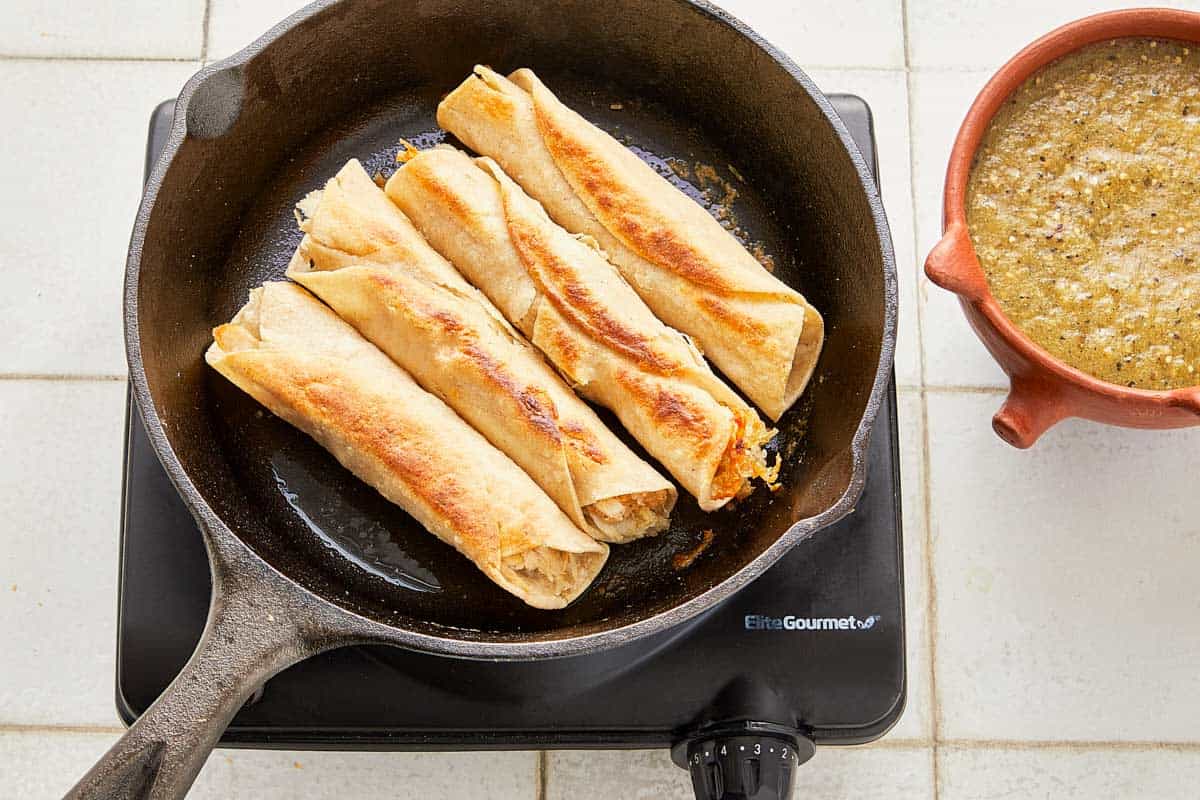 A pan filled with multiple tortillas, heating up for browning enchiladas.