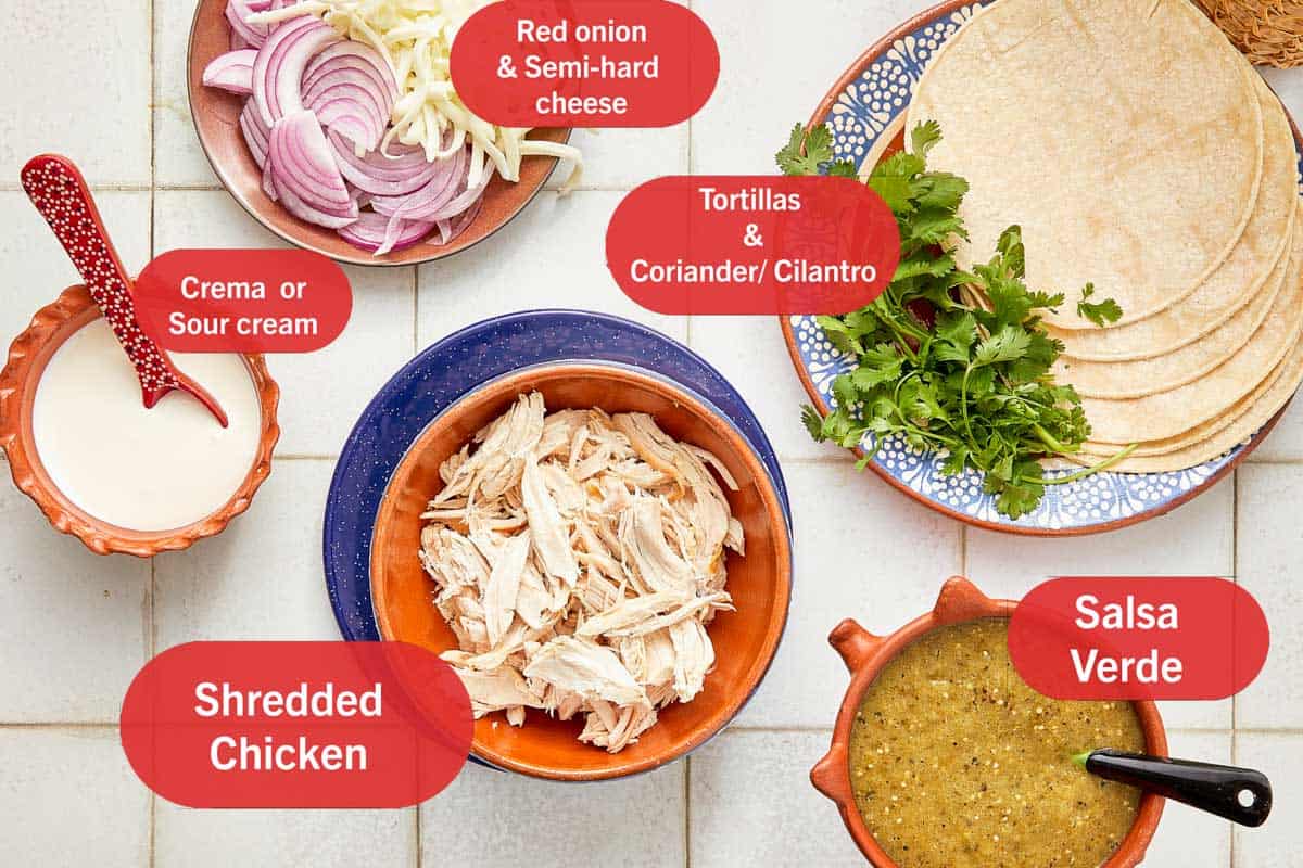 Bowls of ingredients for enchiladas, including tortillas, cheese, and various spices, arranged on a kitchen counter.
