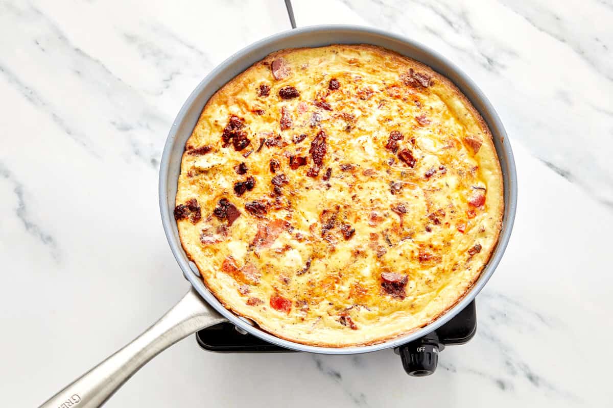 Overhead shot of a sliced frittata served with plates and cutlery.