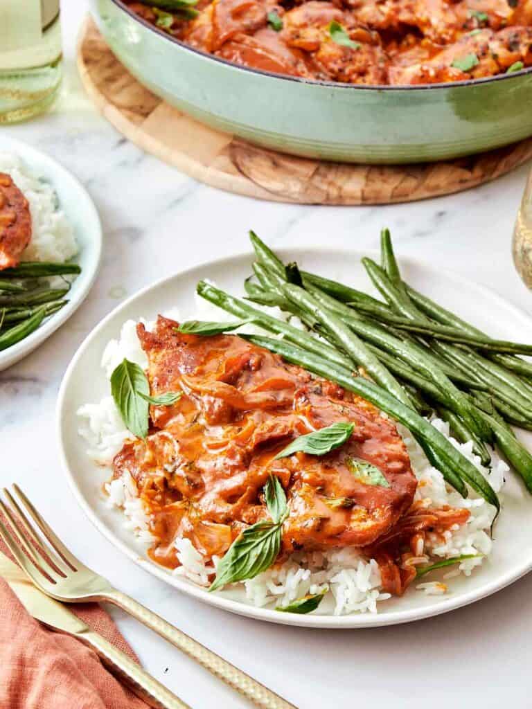 Plated Marry Me Chicken served over white rice with roasted green beans and fresh basil.