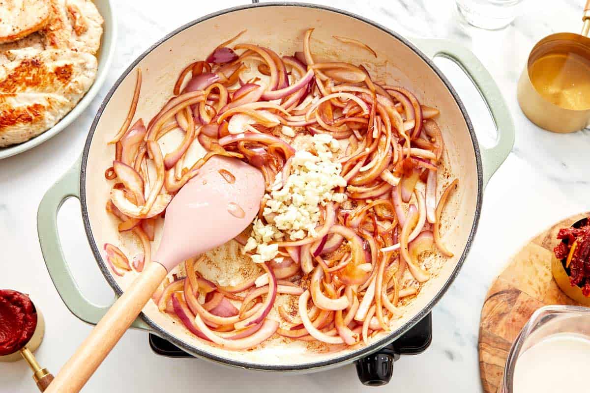 Adding garlic to the sautéed onions in the skillet.