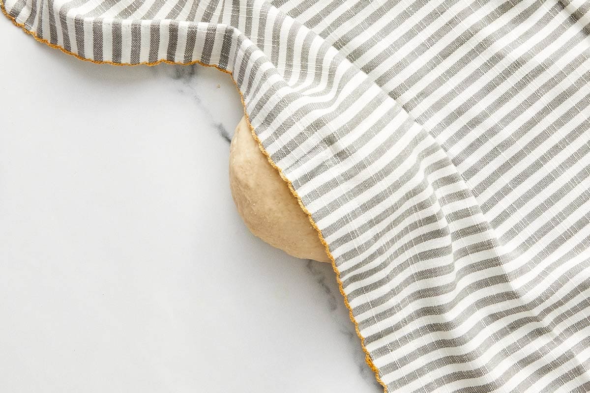 Bao dough resting under a striped tea towel during proofing.