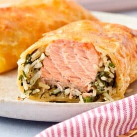 Close-up of a golden Puff Pastry Salmon Parcel sliced open to reveal flaky salmon, creamy spinach, and rice inside.