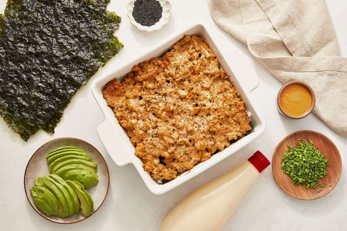 A casserole dish filled with cooked sushi bake, showcasing layers of rice, avocado, and assorted toppings.