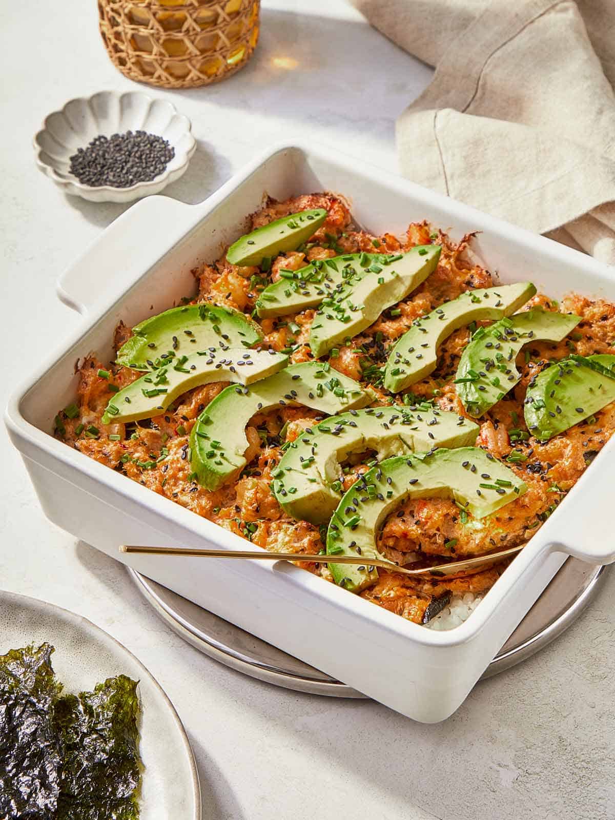 A serving of Sushi Bake garnished with creamy avocado, highlighting the dish's vibrant and inviting appearance.