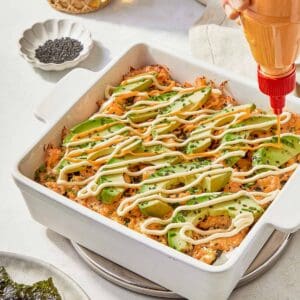 A serving of Sushi Bake garnished with creamy avocado, highlighting the dish's vibrant and inviting appearance.