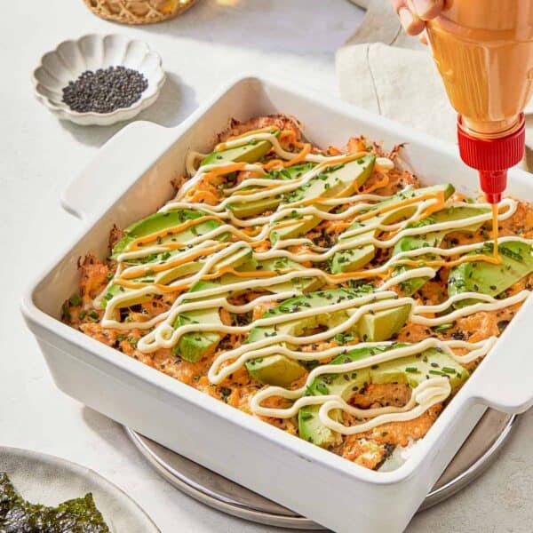 A serving of Sushi Bake garnished with creamy avocado, highlighting the dish's vibrant and inviting appearance.