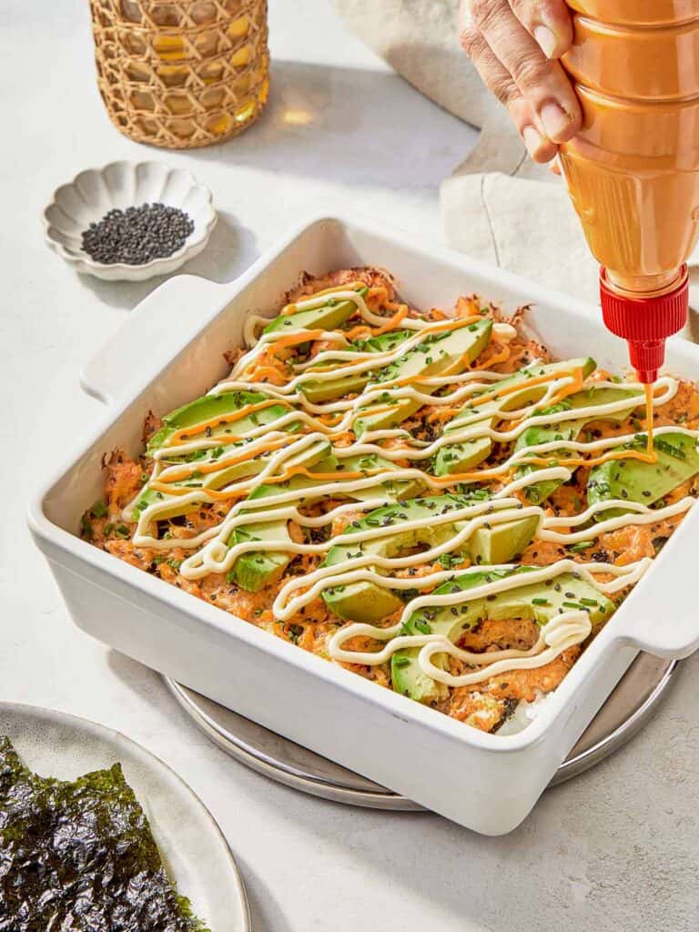 A serving of Sushi Bake garnished with creamy avocado, highlighting the dish's vibrant and inviting appearance.