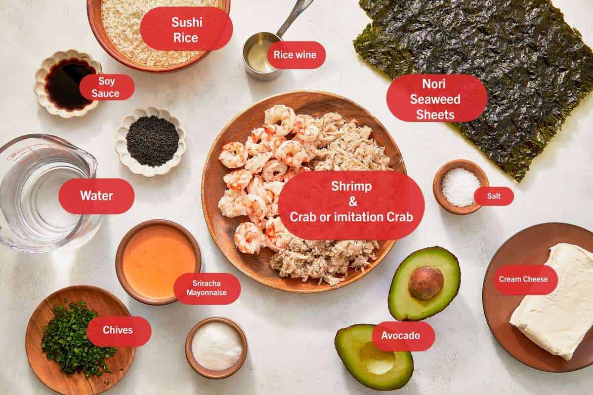 Ingredients for sushi bake neatly arranged on a table, featuring rice, seaweed, fish, and colorful vegetables.