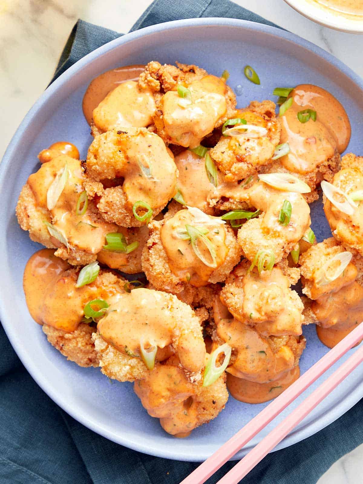 Crispy golden shrimp drizzled with creamy spicy Bang Bang sauce and garnished with green onions.