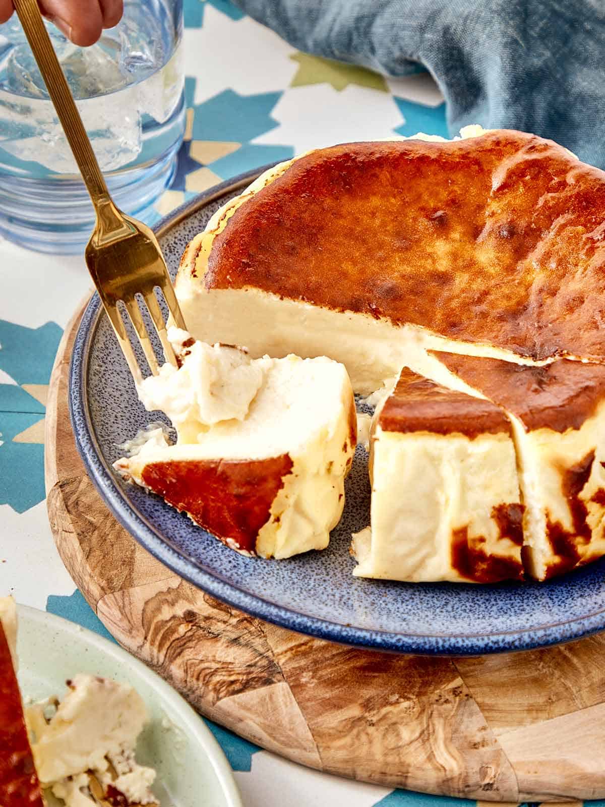 Basque cheesecake slice being cut with a fork on a blue plate