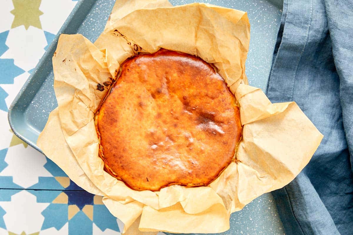 Freshly baked Basque cheesecake in parchment paper inside a baking dish