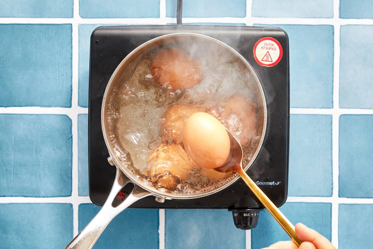 Eggs boiling in a pot on the stovetop.