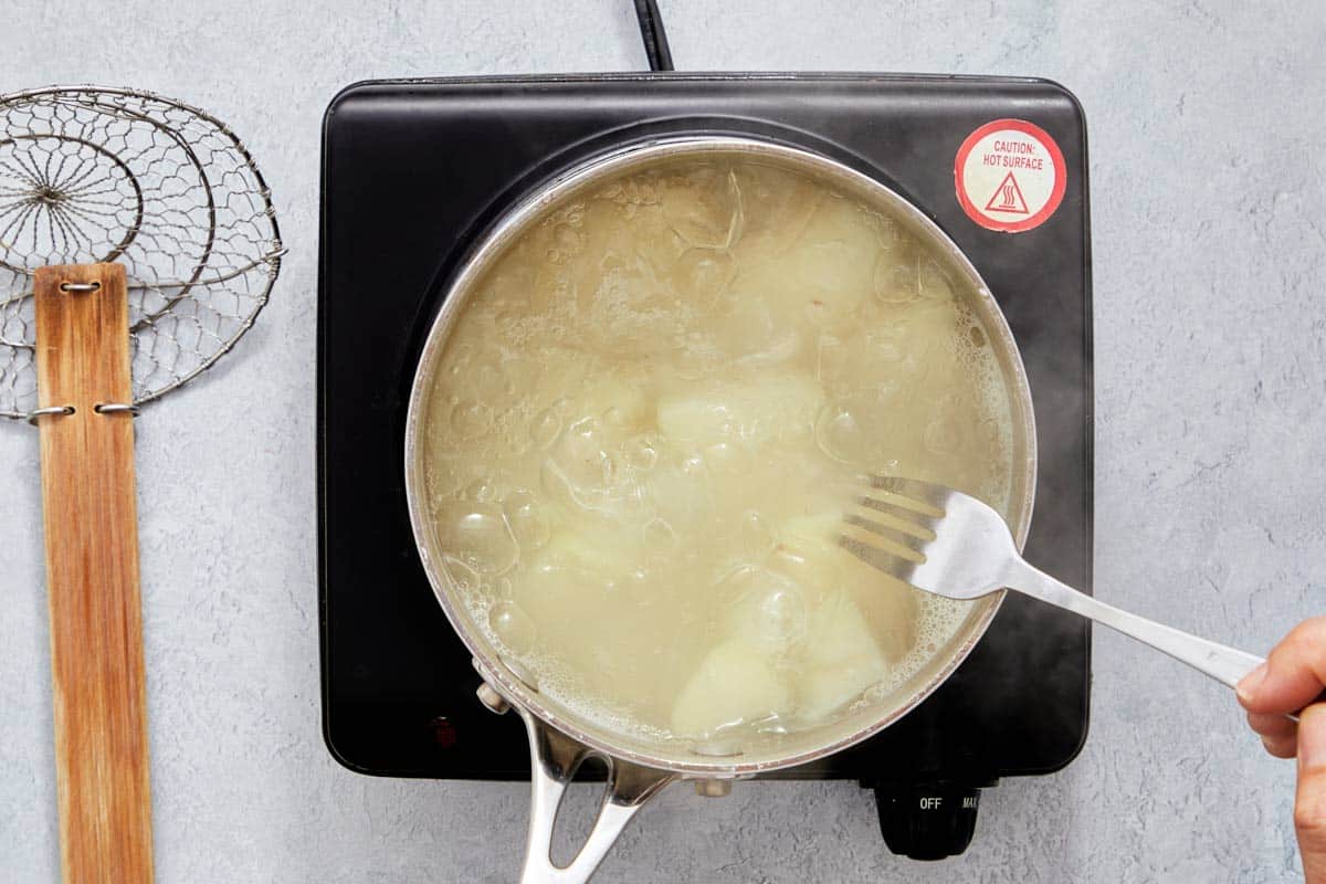 Potatoes boiling in a pot of water on the stove.