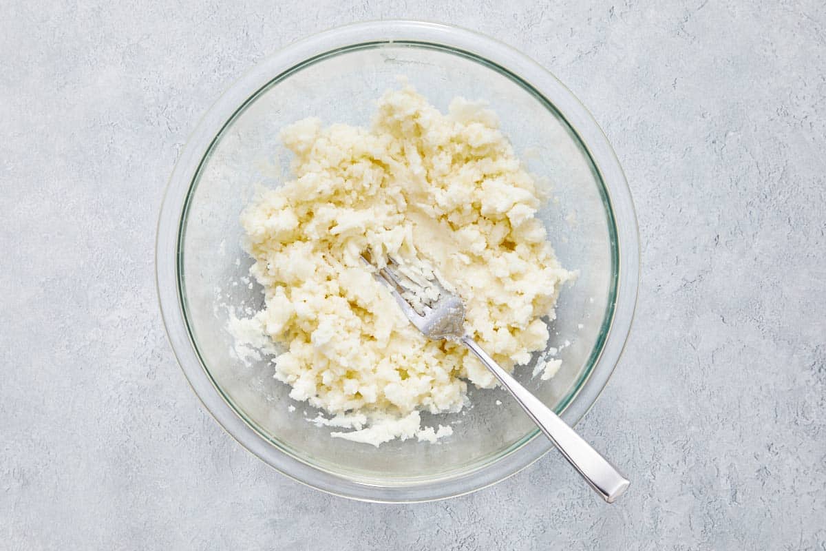 Mashed potatoes in a glass bowl with a fork.