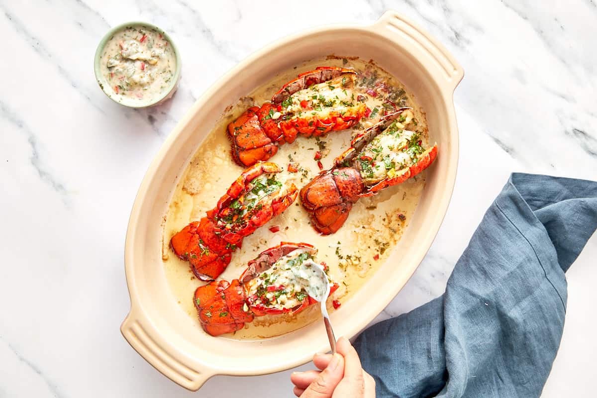 Cooked lobster tails being finished with more chimichurri butter while still hot.
