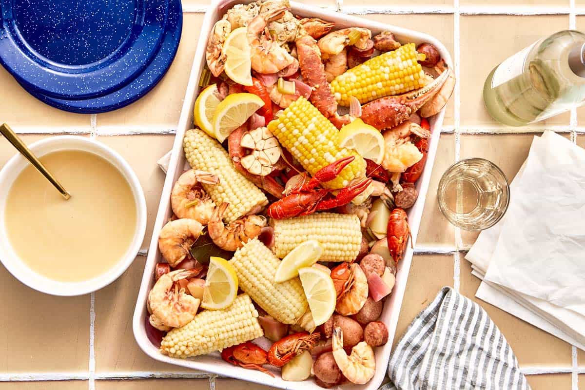 Finished seafood boil served on a tray with corn, shrimp, potatoes, sausage, and dipping sauce on the side.