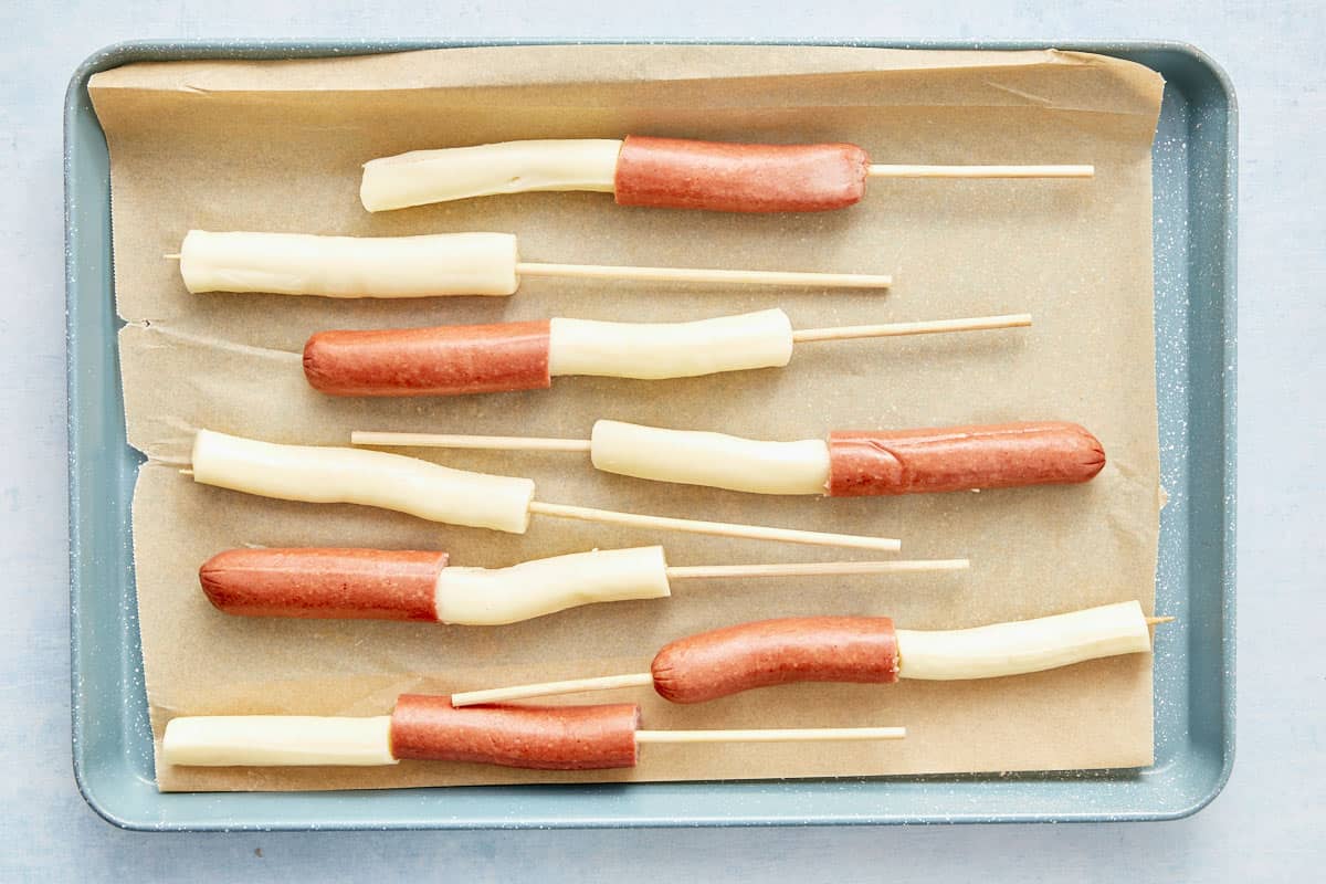 Skewered hot dog and mozzarella sticks on a baking tray, ready to freeze.