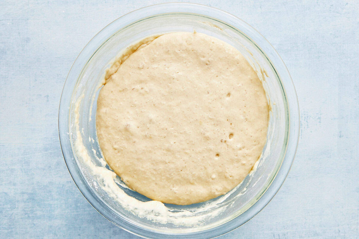 Thick, bubbly batter in a glass bowl after rising.