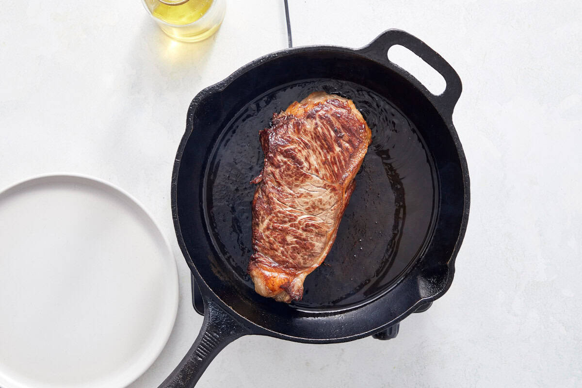 Steak searing in a hot cast-iron skillet.