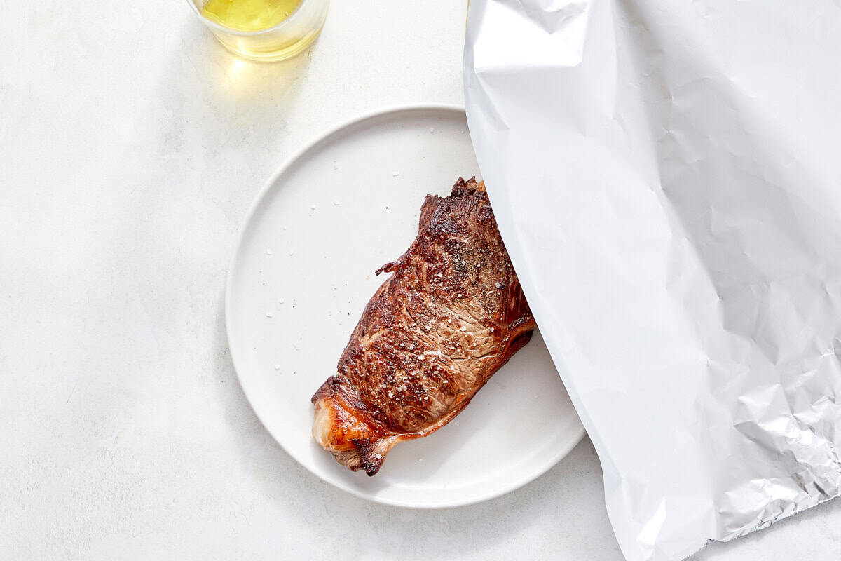 Steak loosely tented with foil to rest.