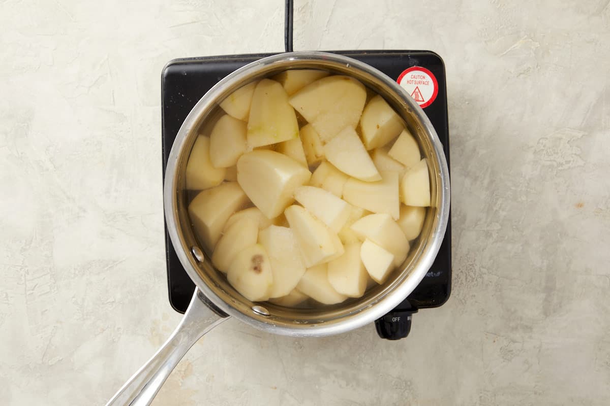 Peeled potato chunks boiling in salted water for the mash.