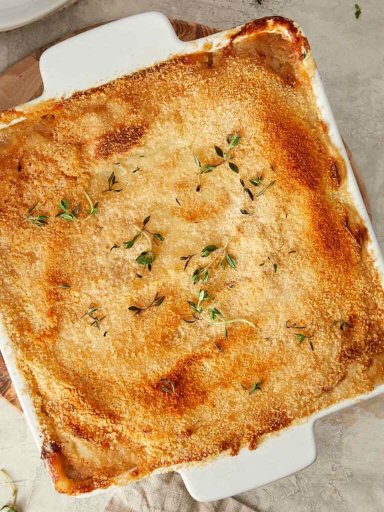 Baked Shepherd’s Pie in a white dish topped with golden breadcrumbs and fresh thyme.