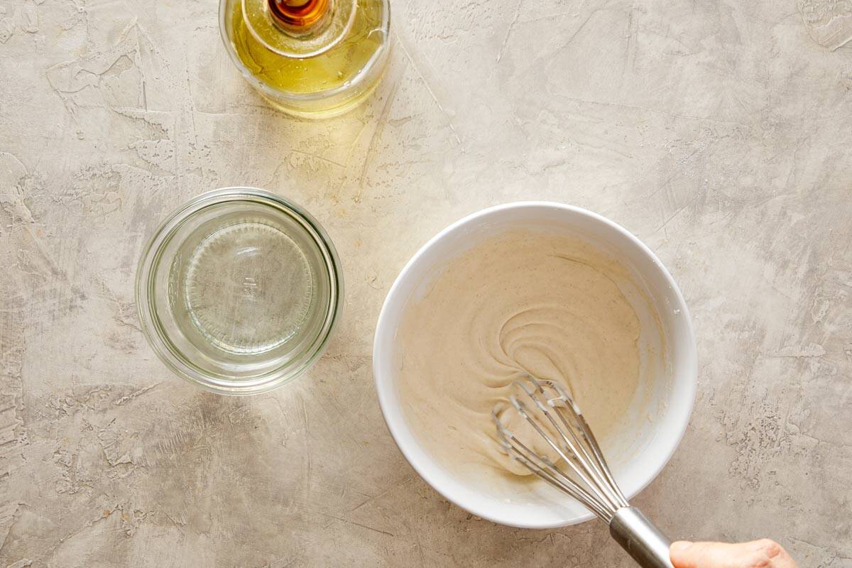 A bowl of smooth batter with a whisk.