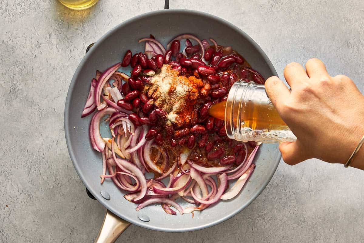 Red beans and sliced onions cooking in a pan with spices