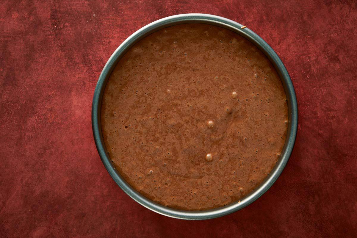 Chocolate chiffon cake batter poured evenly into a round pan, ready for baking.