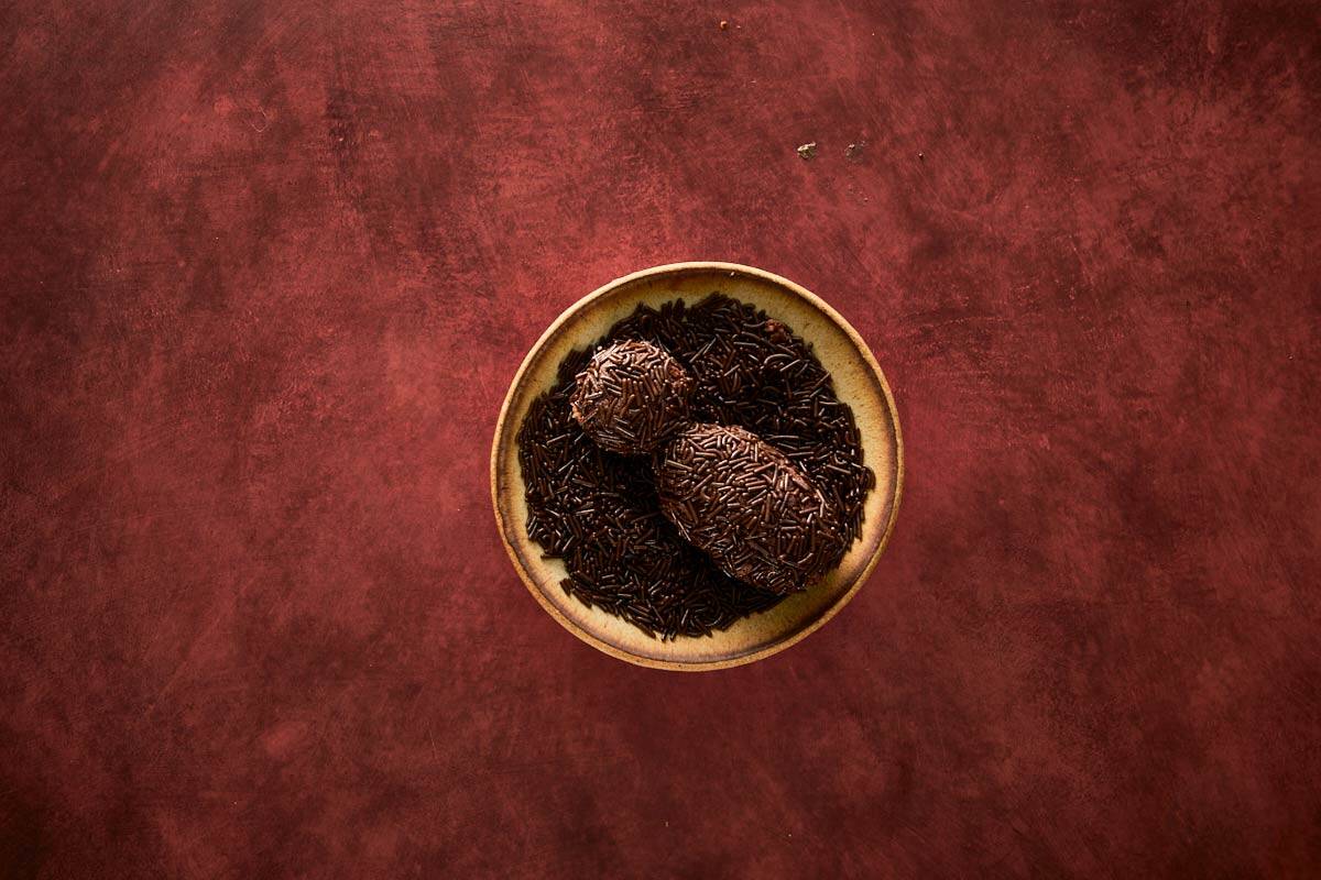 Shaping the chocolate sprinkle–coated spider body using cake crumbs and ganache.