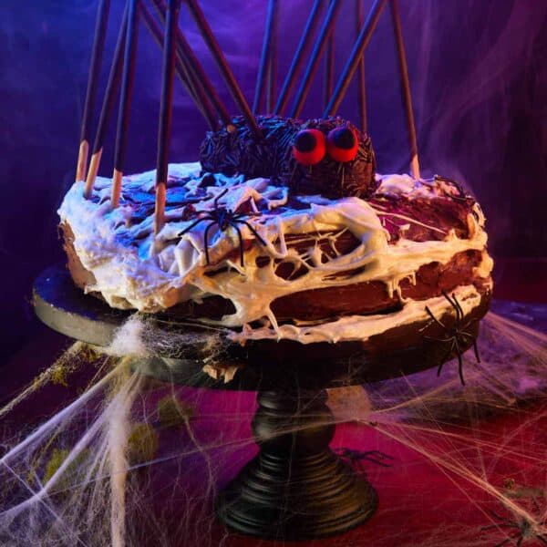 Halloween Spider Cake on display, surrounded by cobwebs and spooky lighting.
