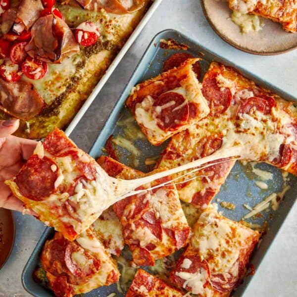 Hand pulling a cheesy slice of focaccia pizza.