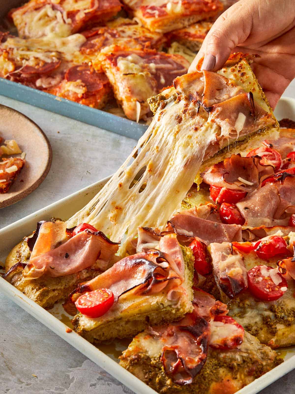 Hand pulling a cheesy slice of focaccia pizza.