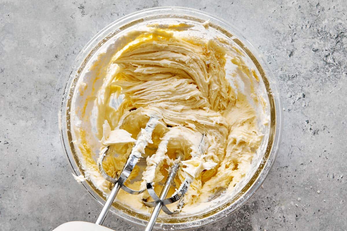 Fluffy vanilla frosting being whipped with an electric mixer.