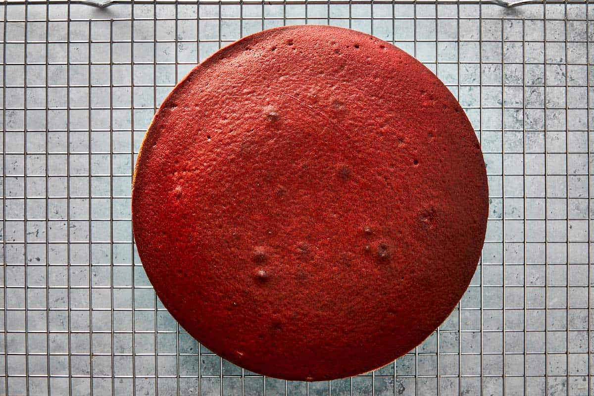 Freshly baked red velvet cake cooling on a wire rack.