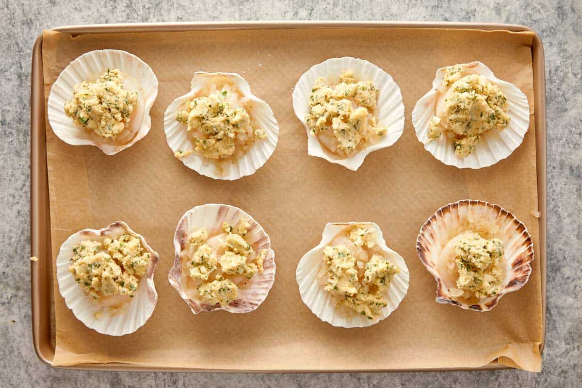 Adding garlic parsley butter on top of each scallop before baking.