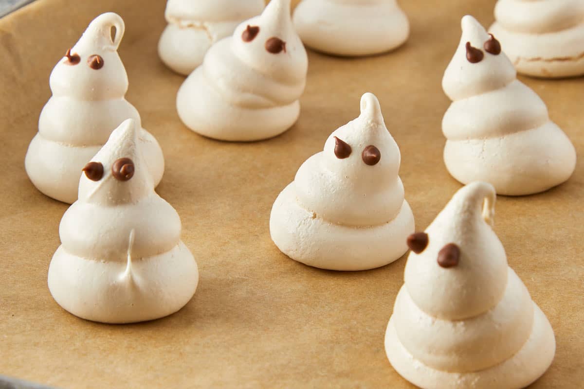 Swiss meringue ghosts and bones cooling on a tray.
