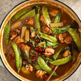 A pot of Thai Green Chicken Curry simmering with chicken pieces, snow peas, bamboo shoots, and kaffir lime leaves in a rich coconut curry sauce. - 17