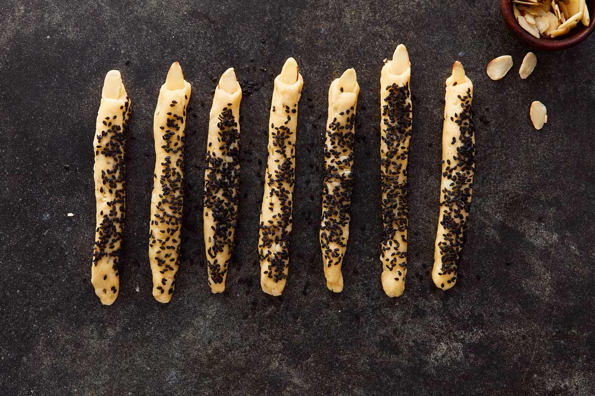 Close-up of shaped fingers topped with almond nails, ready to bake — spooky and detailed.