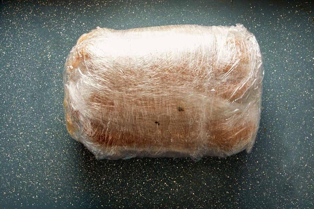 wrapped meat on plastic on a pan