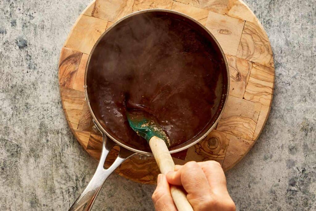 steaming bowl of brown liquid on top of a wooden board