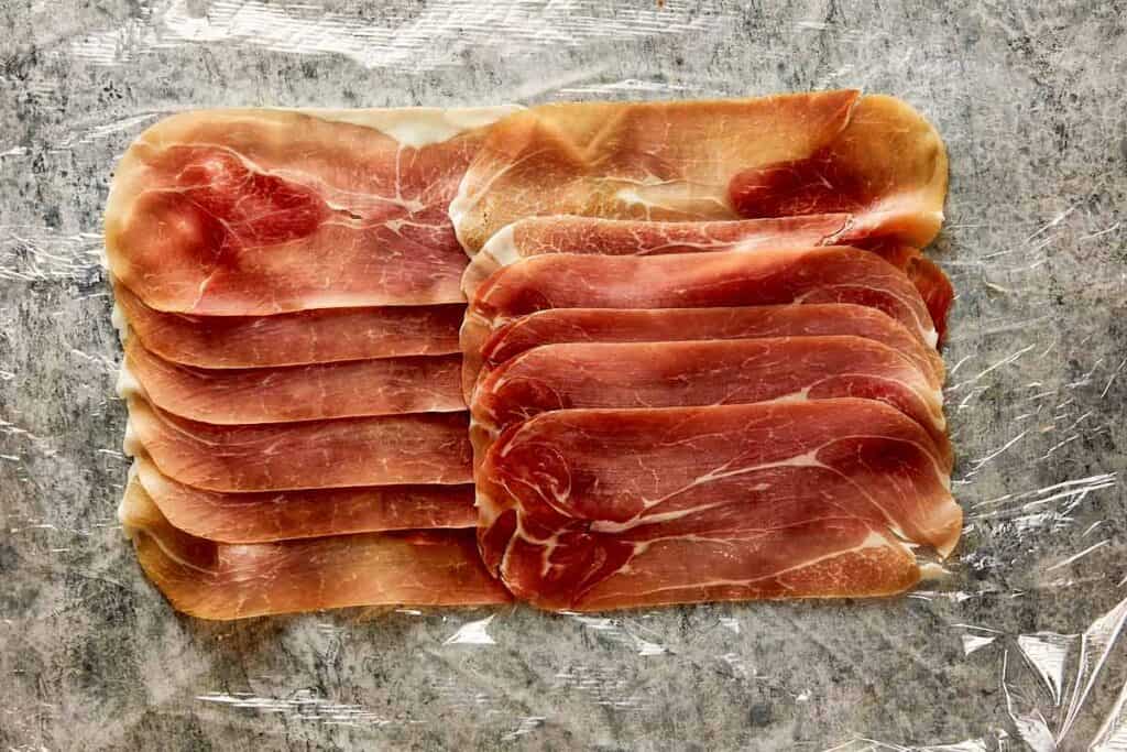 prosciutto layed out in layers ready to wrap in the meat