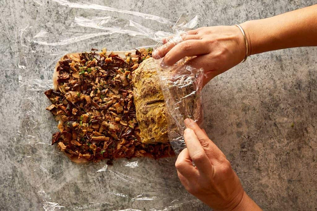 rolling the meat on top of the chopped mushrooms
