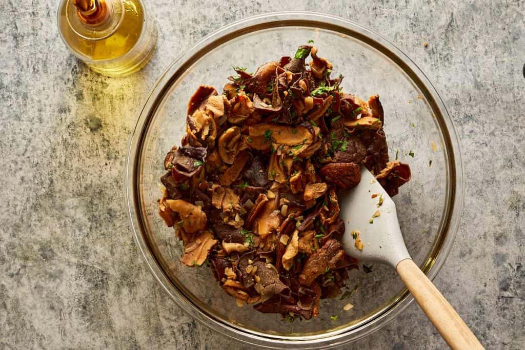 bowl of chopped mushroom mix being mixed with a wooden spoon.