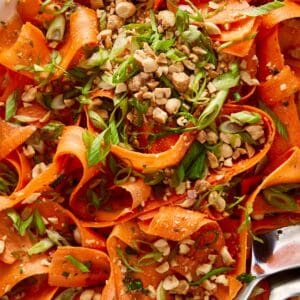 carrot salad with peanuts on top and a spoon on the side