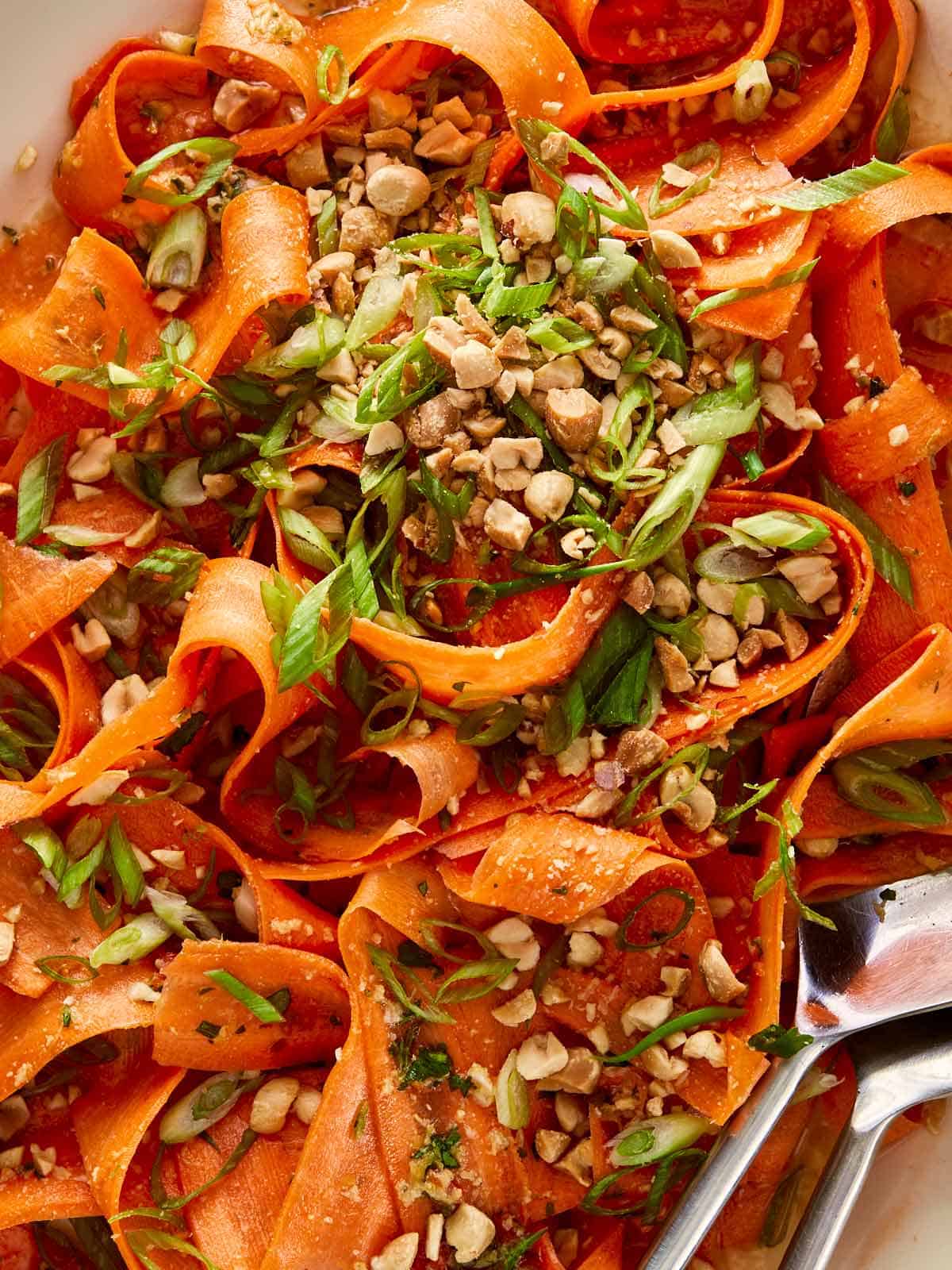 close up top down of carrot salad dressed with peanuts and green onion